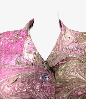Close-up of the collar of a pink and brown marbled silk jacket on a white background