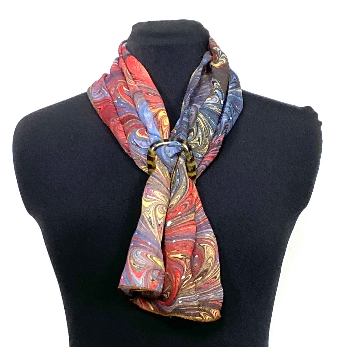 Colorful marbled silk scarf on a black mannequin against a white background