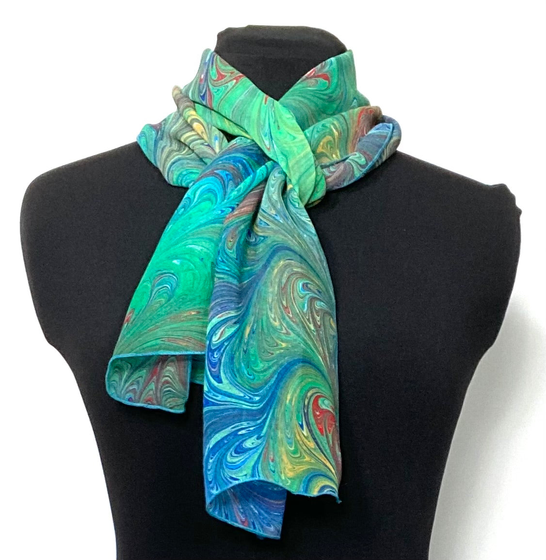 Colorful scarf with swirling pattern draped over a black mannequin on a white background