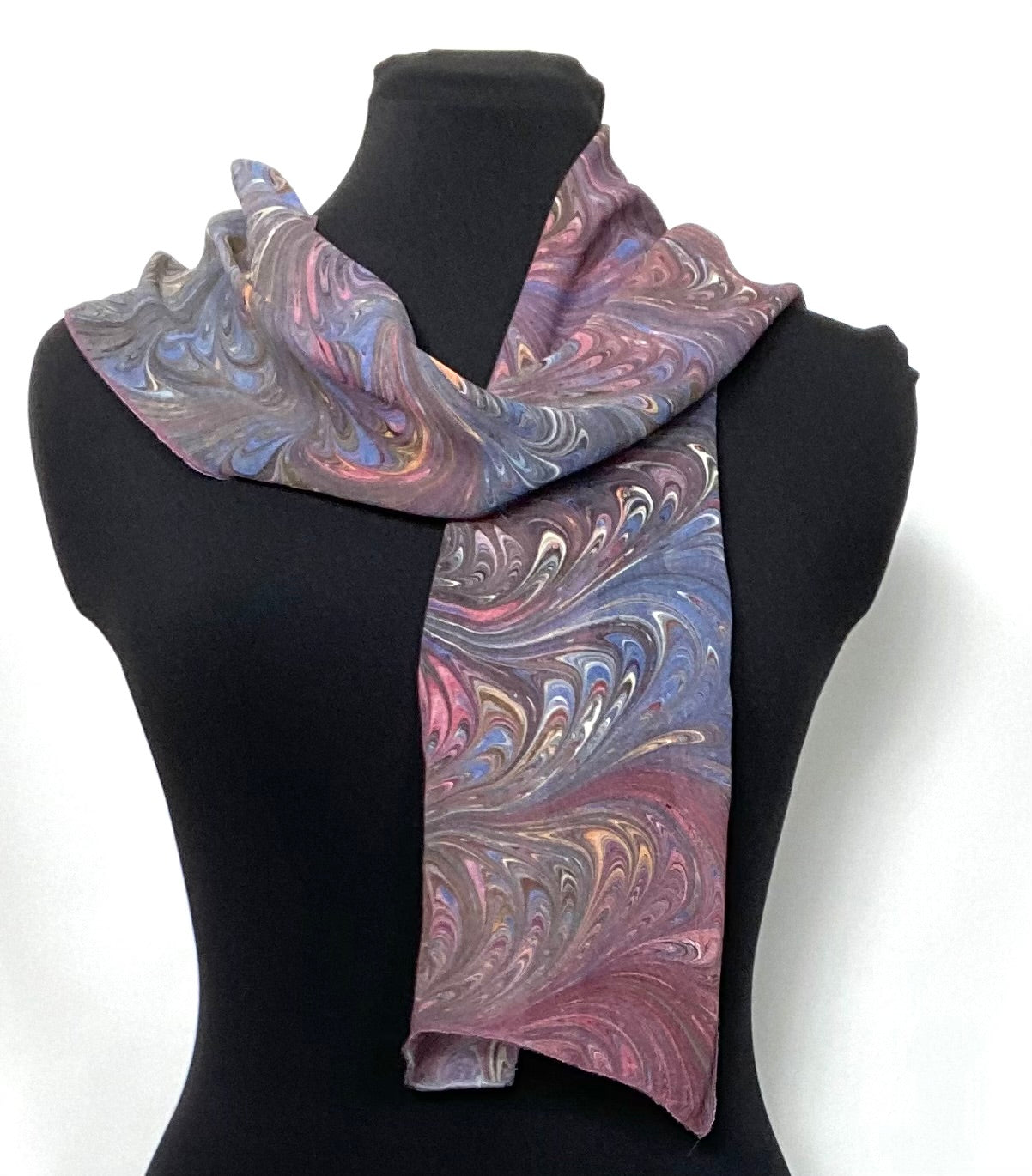 Marbled patterned scarf on a black mannequin against a white background