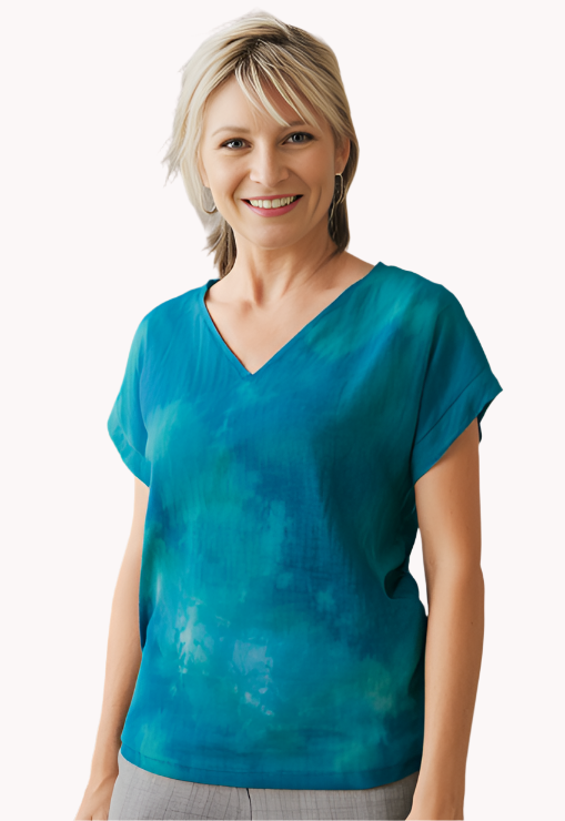 Woman wearing a hand dyed jade silk top and gray pants standing against a plain background