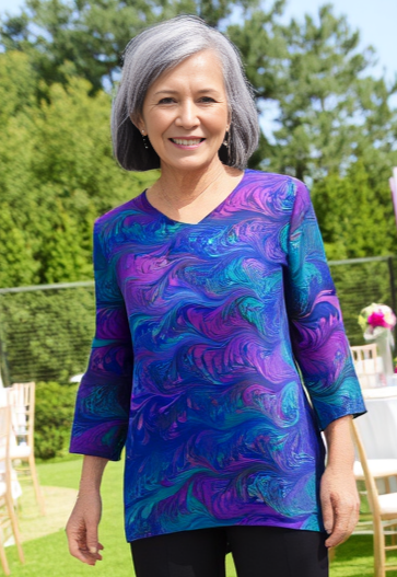 Woman standing outdoors wearing a marbled black jewels silk tunic in a garden party
setting