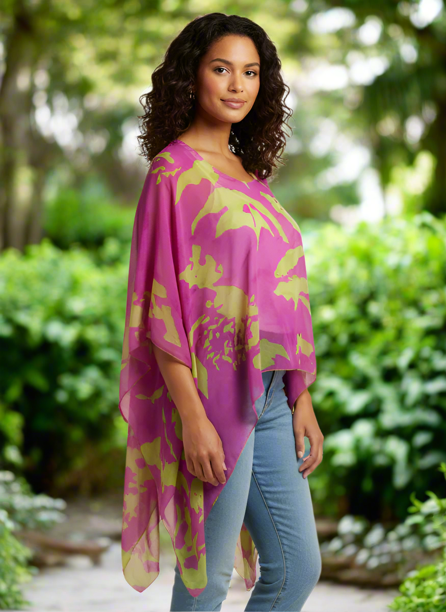 Woman wearing a pink and green abstract patterned poncho with jeans on a beige background
