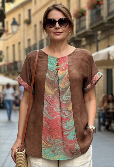 Woman walking down a street wearing a brown top with marbled silk inset and beige pants.