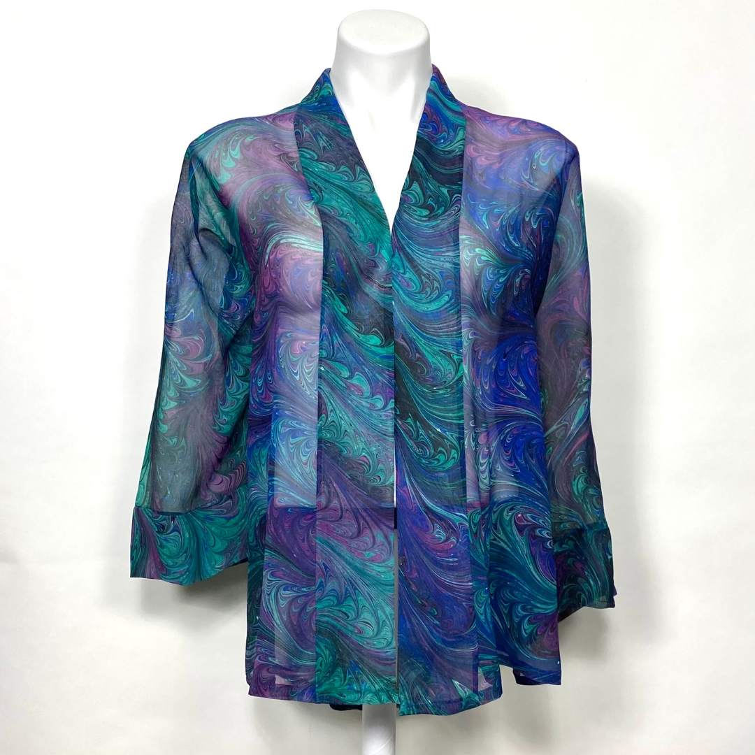 Hand marbled silk kimono jacket in blue, green, violet and black colors on a mannequin against a white background