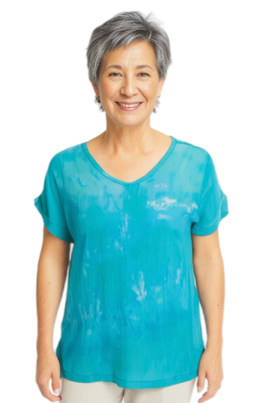 Woman wearing a hand dyed silk jade shirt and beige pants on a white background