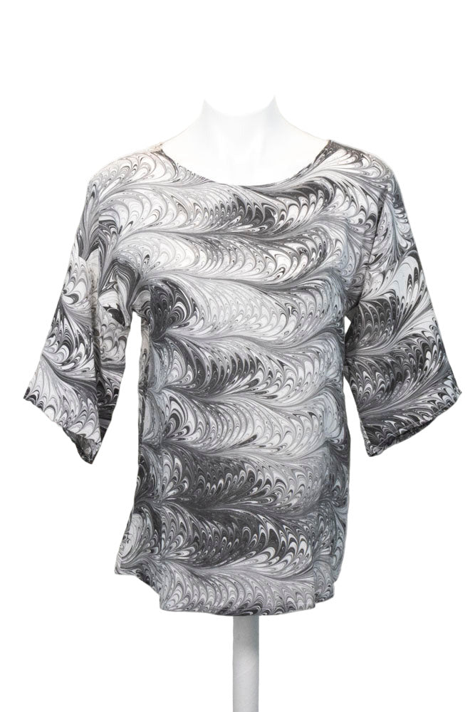 Mannequin wearing a black and white marbled silk blouse against a white background