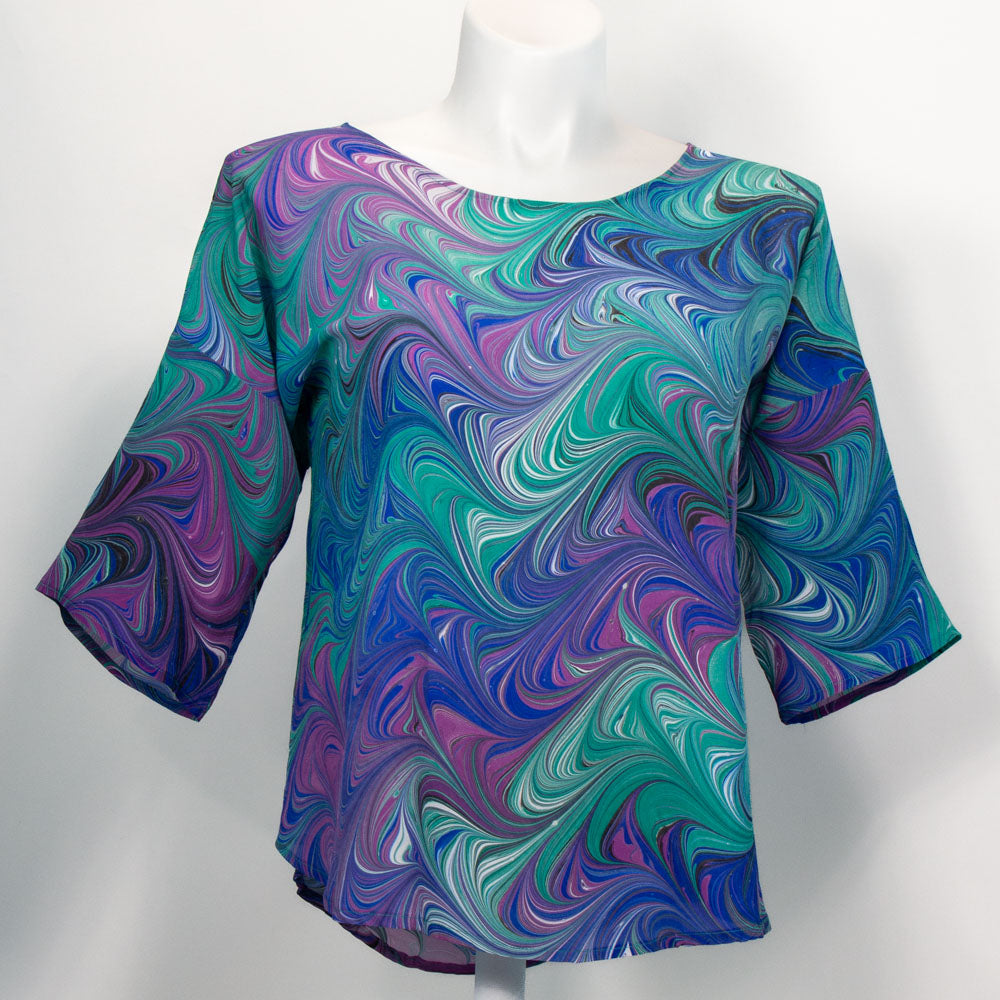 Marbled silk blouse in bright blue, violet, black, and white on a mannequin against the white background