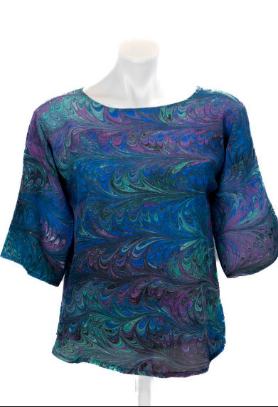 Marble silk top in black blue, green and violet on a mannequin against a white background
