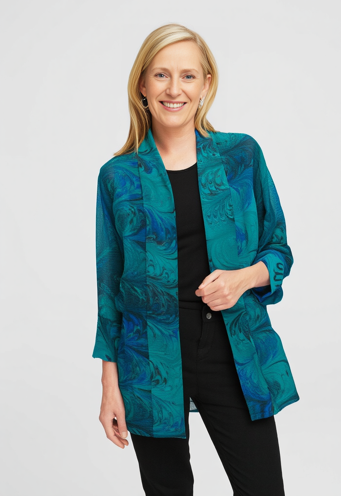 Woman wearing a teal and black marbled silk sheer jacket on a white background