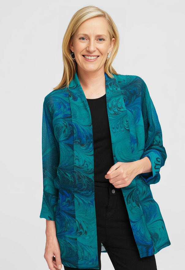 Woman wearing a teal and black marbled silk sheer jacket on a white background