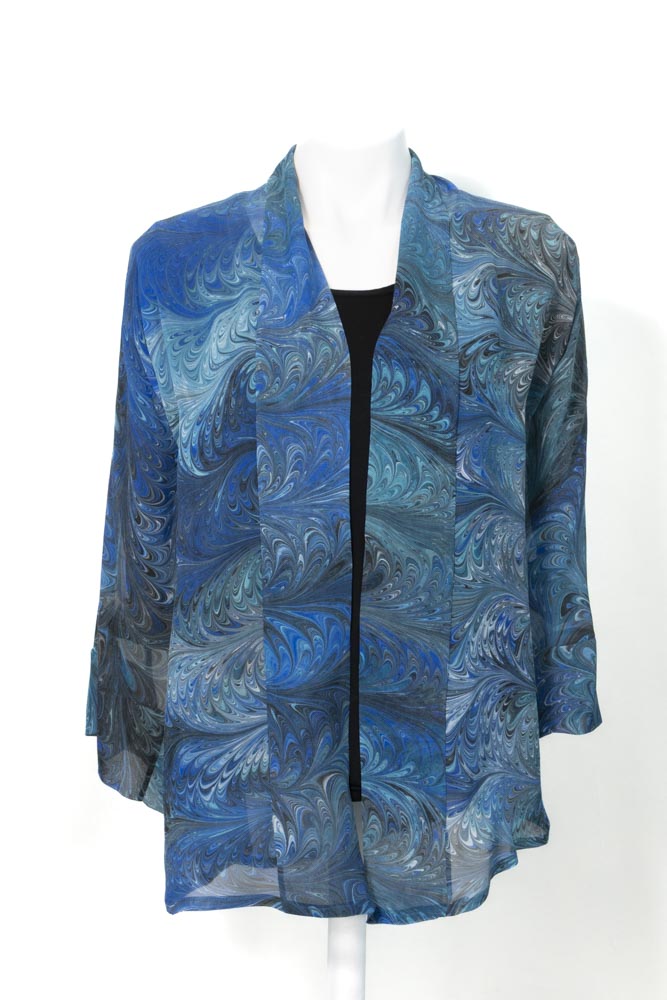 A deep turquoise blue sheer jacket with blue, aqua, black and white marbled patterns displayed on a mannequin. The jacket has loose sleeves