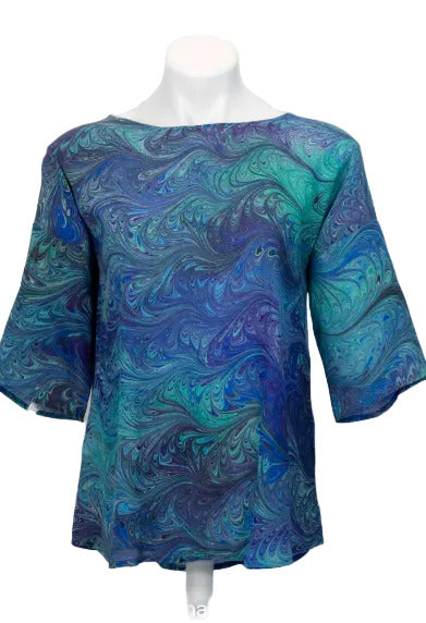Blue and green marbled silk blouse on a mannequin against a white background