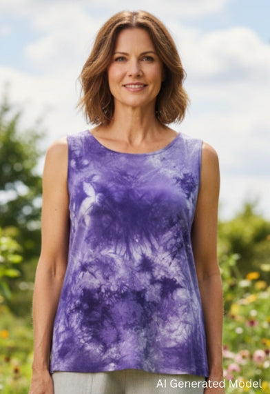 Woman wearing a purple hand dyed silk top and light gray pants standing in a garden.