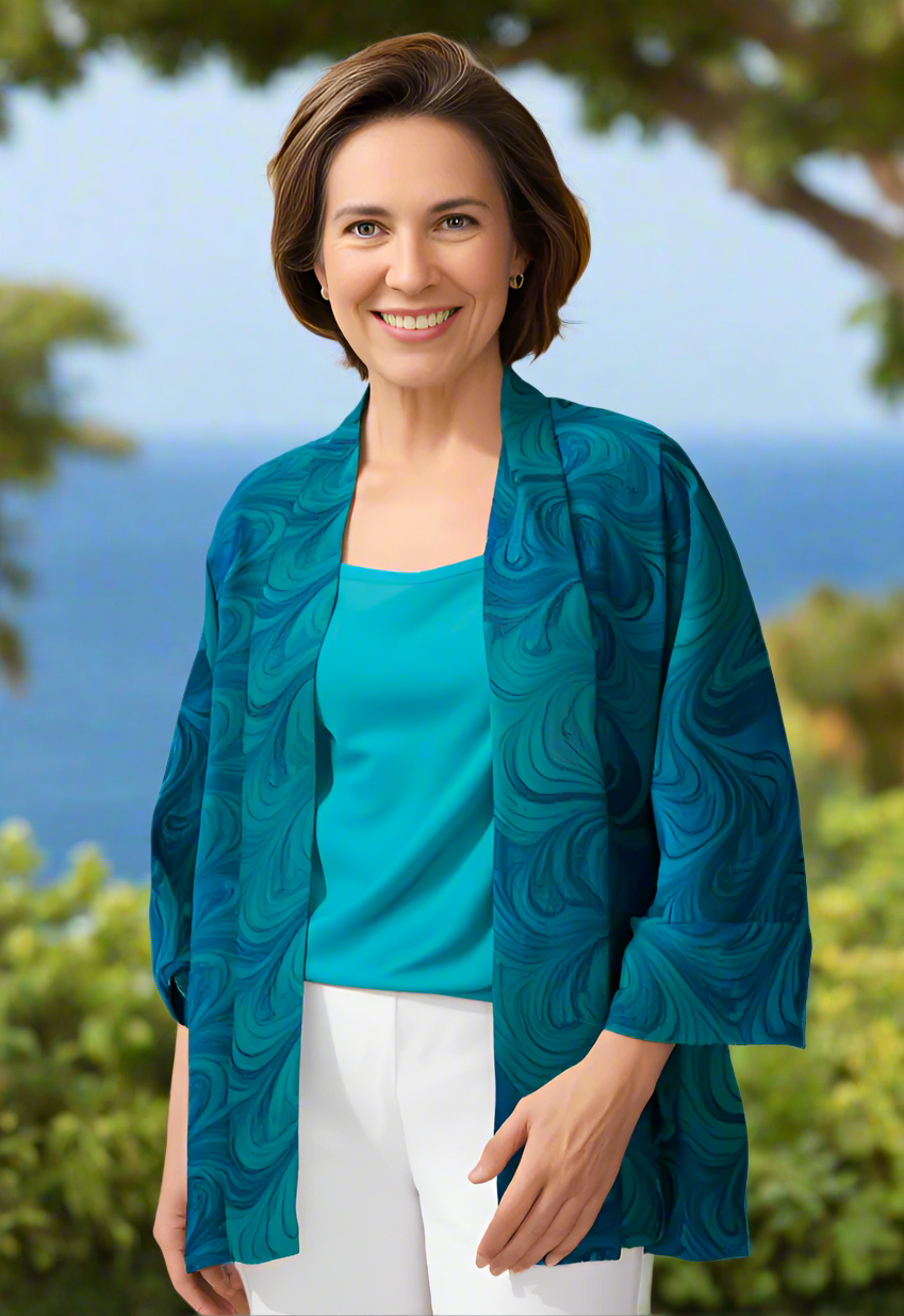 Woman wearing a blue marbled silk sheer jacket over a turquoise top with a blurred natural background