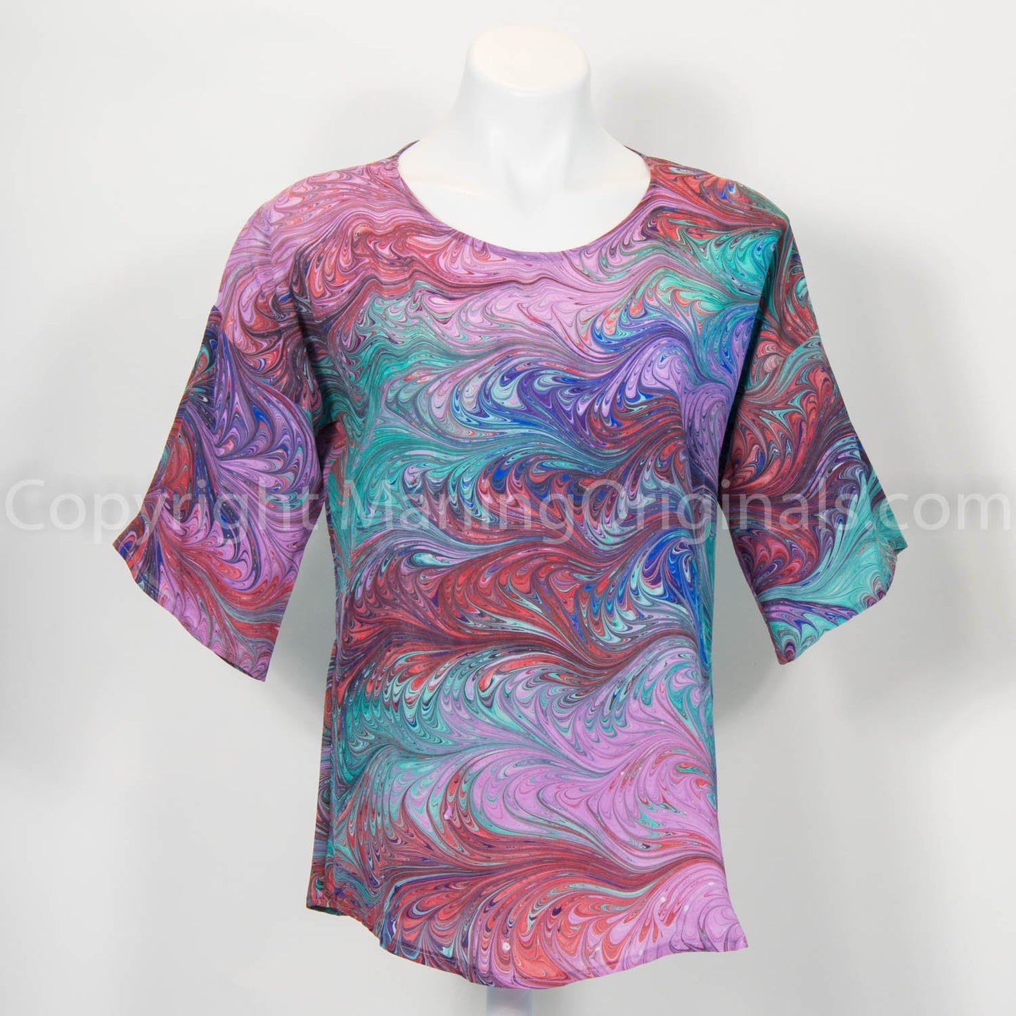 Marbled silk blouse with half sleeves and pink’s red and blue on a mannequin against a white background