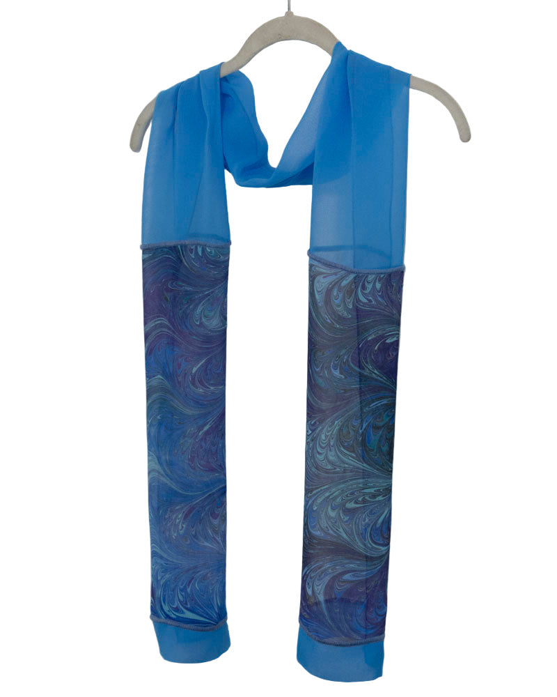 Blue scarf with marbled pattern on a hanger against a white background