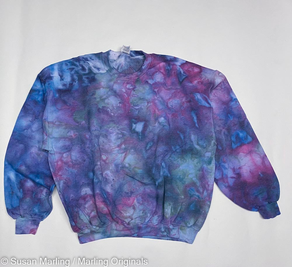 Ice dyed sweatshirt in Violet and blue laying against a white background