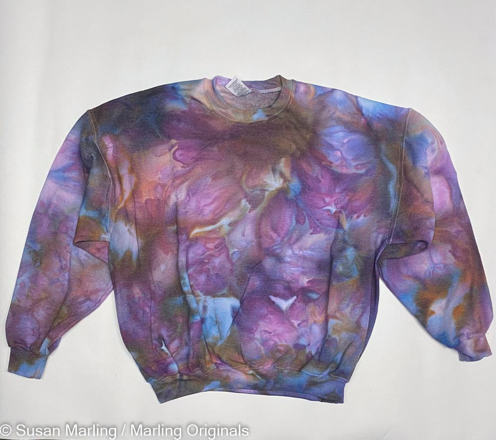 Ice dyed sweatshirt In blue purple and rust laying against a white background