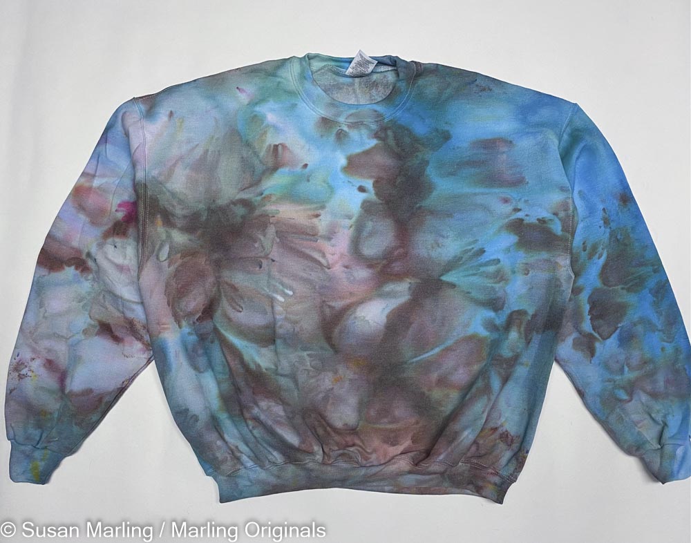 Ice dyed sweatshirt and blue and brown, laying against a white Background