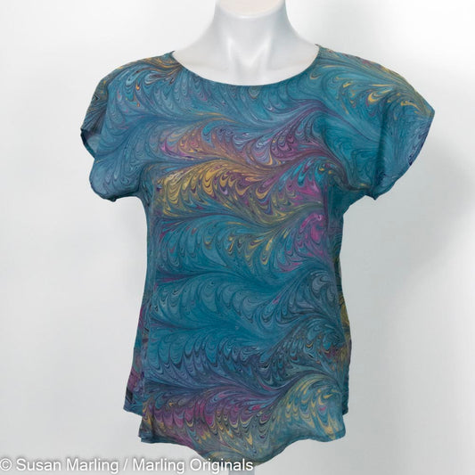 Marvel silk, short sleeve blouse in turquoise, fuchsia and gold on a mannequin against a white background