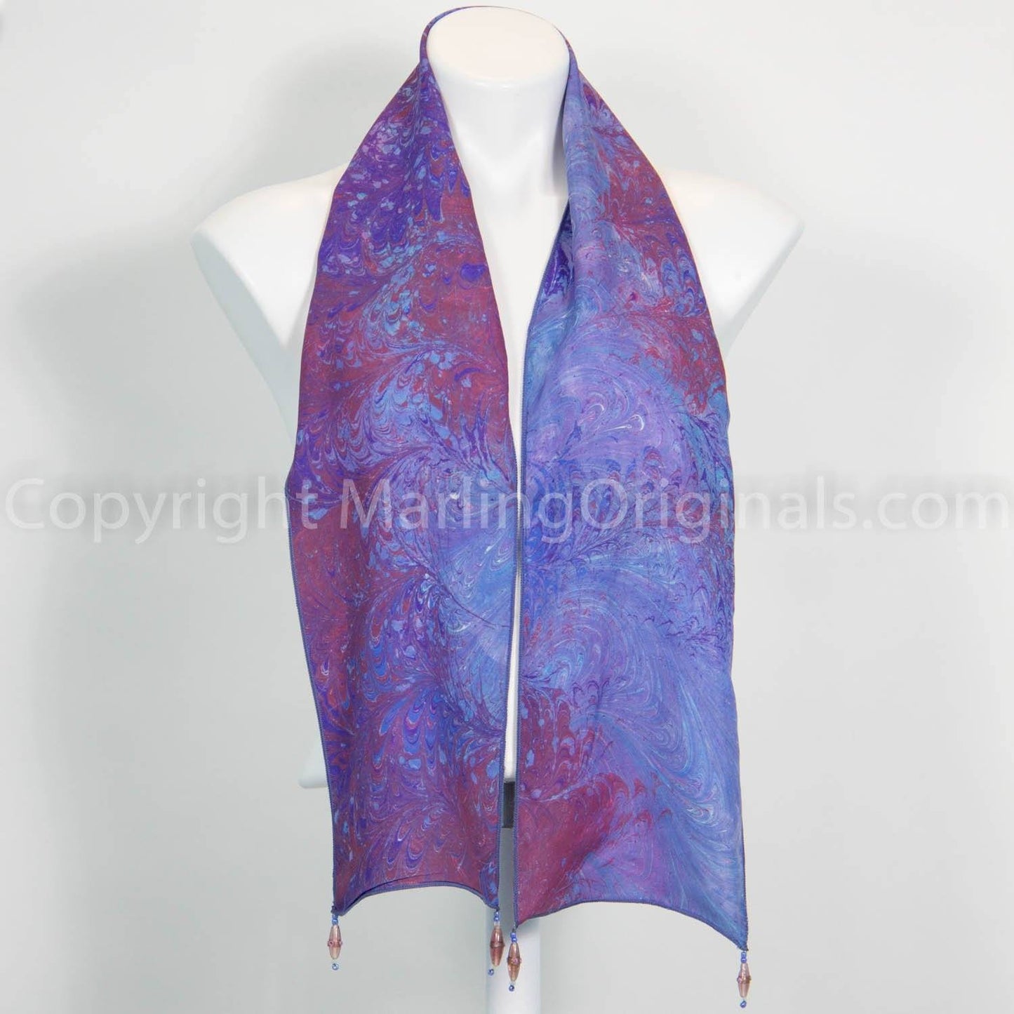 silk scarf marbled in blue and red. Blue scarf has bead dangles at each corner