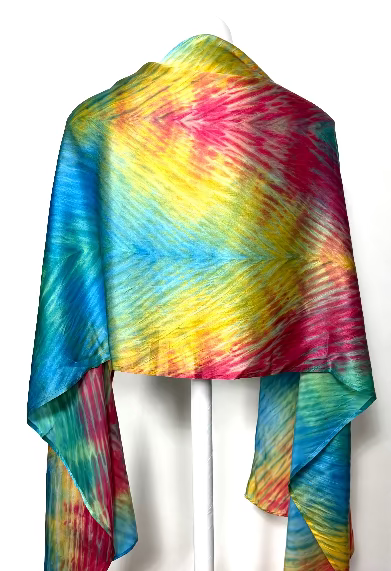 Colorful shibori dyed silk scarf worn as a shawl - back view -  draped over a white background