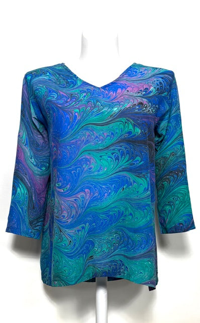 Blue and green marbled silk top on a mannequin against a white background