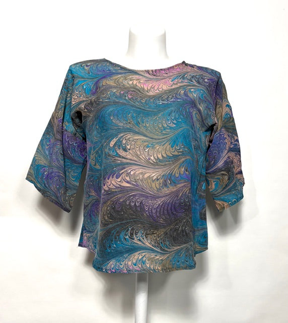 Marbled silk blouse on a mannequin against a white background