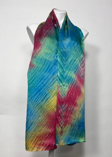 Colorful tie-dye shirt silk scarf on a white surface with a cardboard box in the background