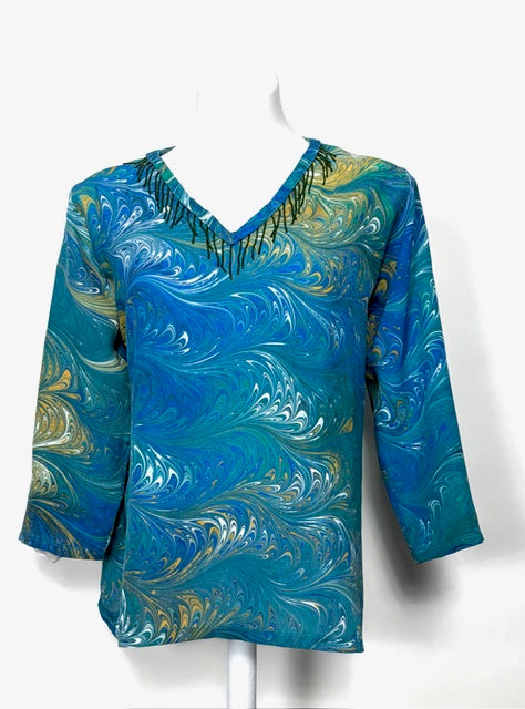 Blue marbled silk shirt on a white mannequin against a white background