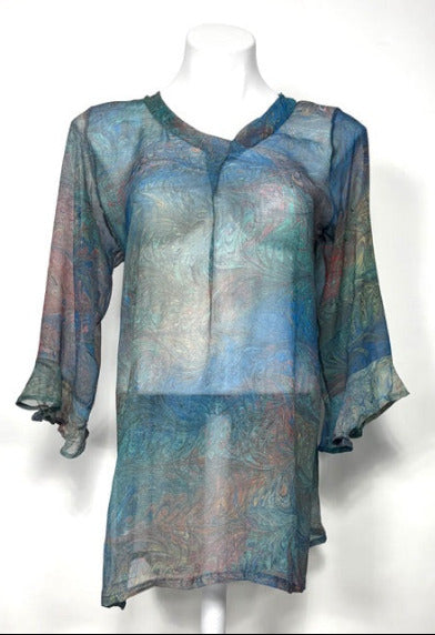 Sheer, multicolored marbled silk blouse on a mannequin against a white background