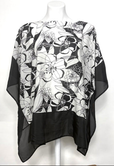 Black and white floral patterned poncho with a black border on a mannequin against a white background