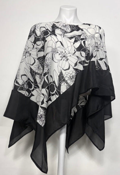 Black and white graphic floral patterned poncho on a mannequin against a white background