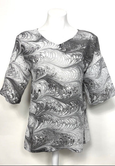 Mannequin wearing a black and white marbled silk  blouse on a white background