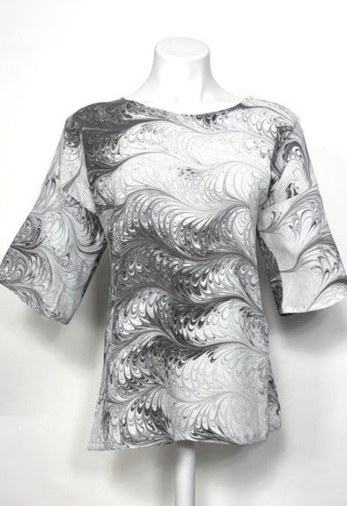 Mannequin wearing a black and white marbled silk blouse on a white background