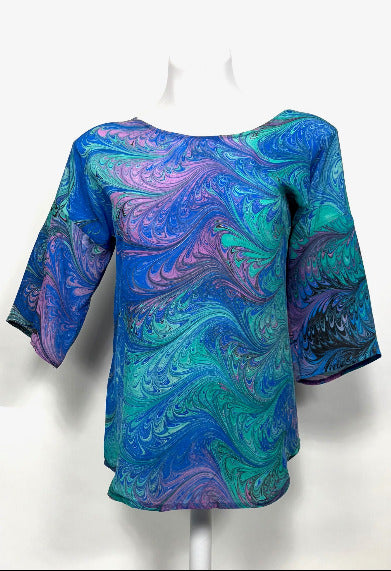 Blue and green marbled silk top on a white mannequin against a white background