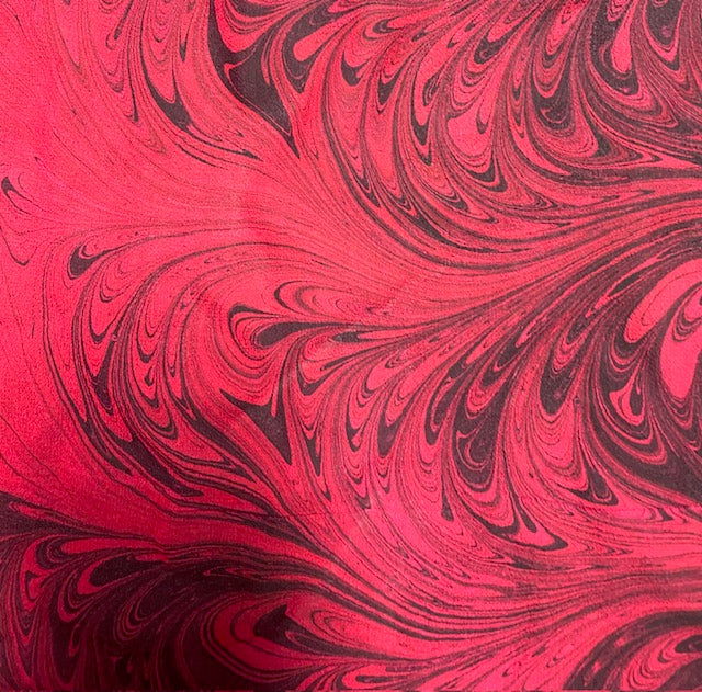 Marbled scarf closeup with swirling patterns of red and black.