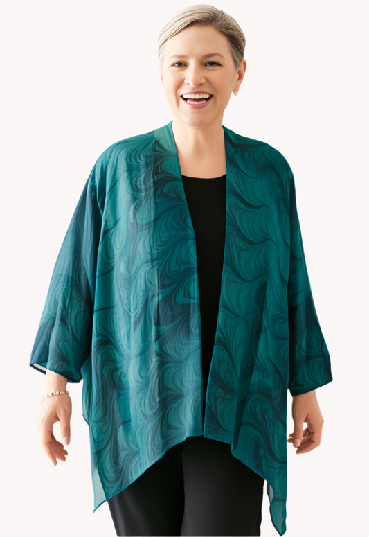 Woman wearing a teal marbled flowing silk wrap/jacket against a white background