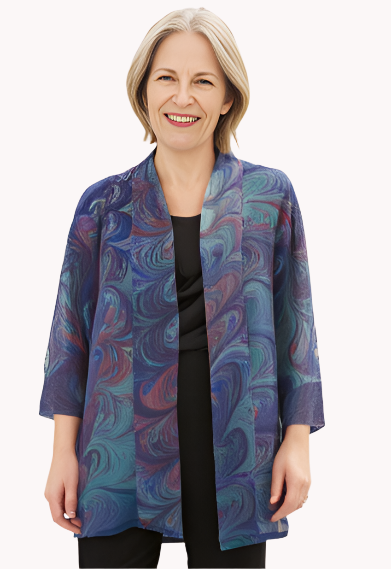 Woman wearing a marbled silk sheer jacket over a black top and pants on a white background
