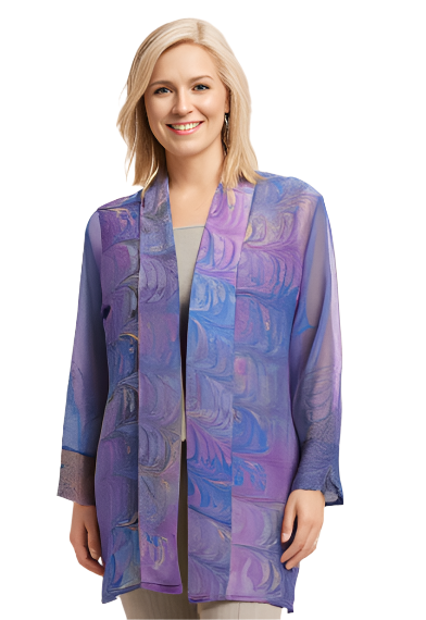 Woman wearing a hand marbled silk jacket in lavender, blue and peach with   beige pants on a beige background