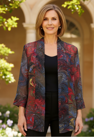 Woman wearing a colorful marbled silk  jacket outdoors with greenery and architecture in the background