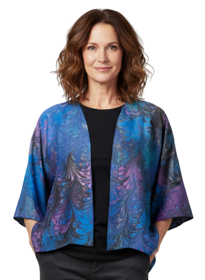 Woman wearing a blue and purple marbled silk satin jacket with black pants on a plain background