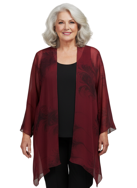 Woman wearing a marbled red and black kimono-style jacket over a black outfit on a plain background