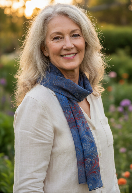 Woman wearing a marbled silk scarf outdoors with blurred greenery in the background