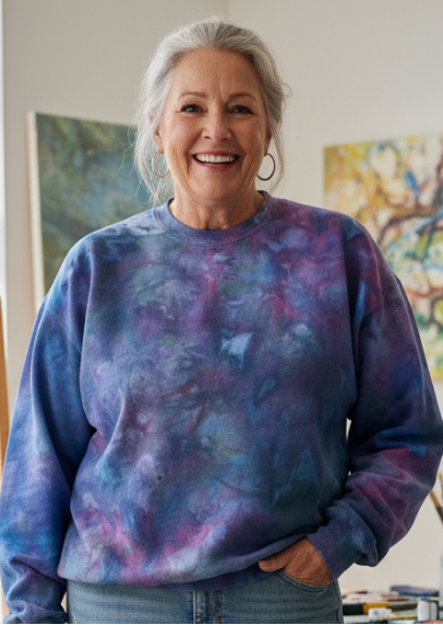 Woman standing in an art studio wearing an ice dyed sweatshirt and jeans.