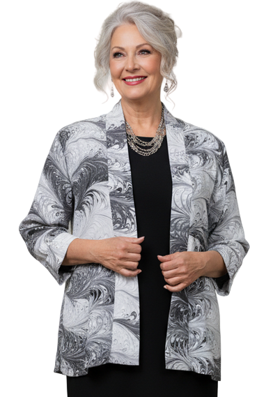 Woman in a marbled silk white and black jacket with black dress standing against a white background