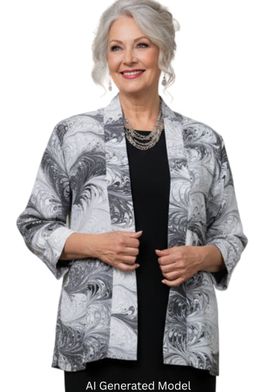 Woman in a marbled silk white and black jacket with black dress standing against a white background