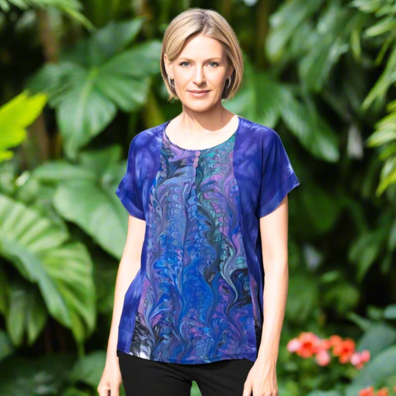 Woman wearing a hand, dyed and marbled silk blouse with black pants in a botanical garden against