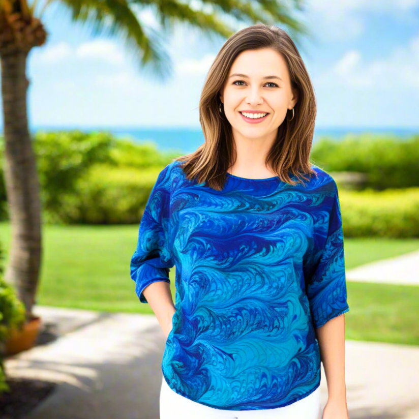 Woman wearing a blue and aqua marbled patterned shirt on a white background